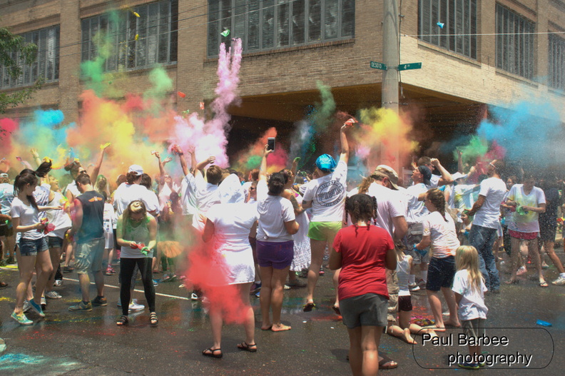 People throwing various colors on a city street corner